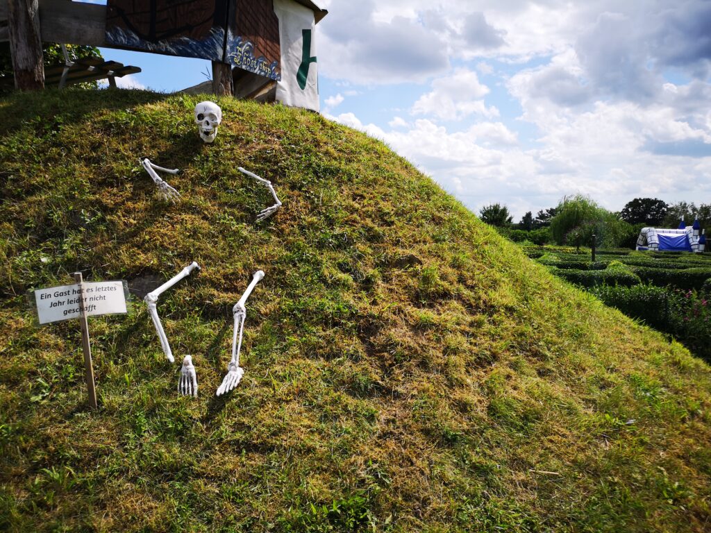 Auf einem Hügel wurde ein künstliches Skelett halb vergraben am Eingang zum Irrgarten